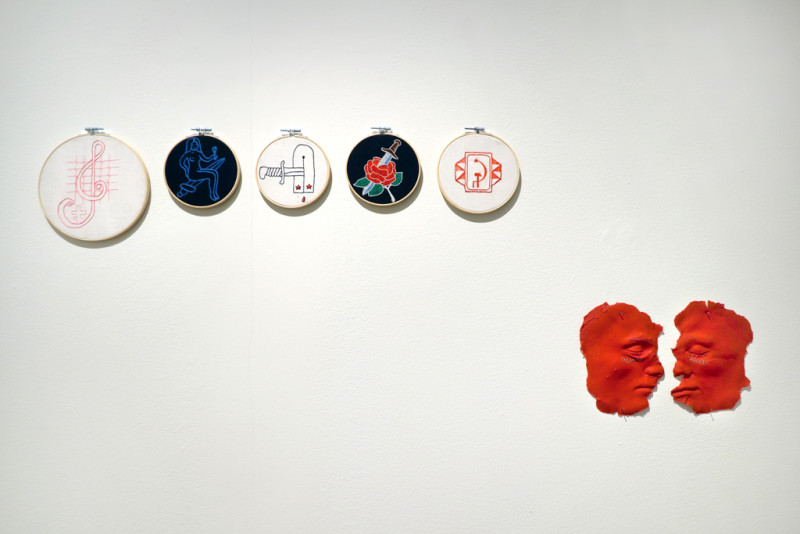 Fünf runde Stickereien mit Symbolen aus der Gefängniskultur Sibiriens. Rote Abformungen zweier Gesichter, die flach an die Wand genagelt wurden of Siberia. Red molding of two faces nailed flat to the wall.