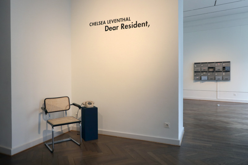 ein Stuhl steht in der Ecke und daneben ein Telefon auf einem blauen Sockel