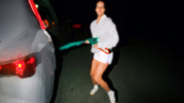 Das Bild zeigt eine Person, die unscharf fotografiert ist und auf einer Straße steht, neben ihr ist ein Auto zu sehen.