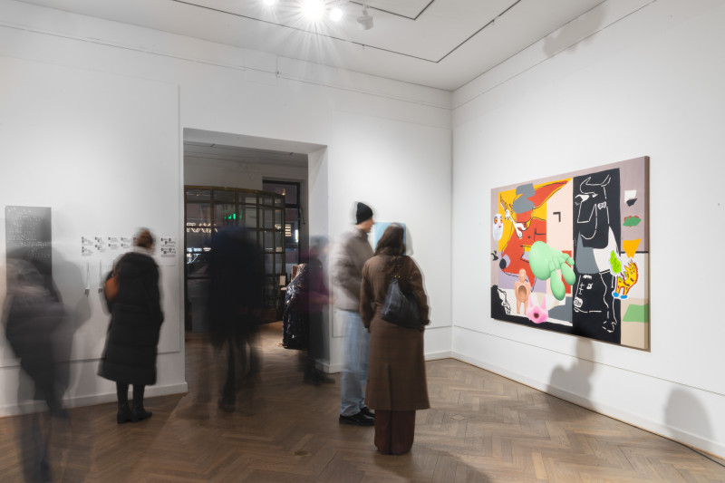 Man sieht den Galerieraum, rechts im Bild ein großes buntes Gemälde, davor verschwommene Menschen, die sich durch den Raum bewegen.