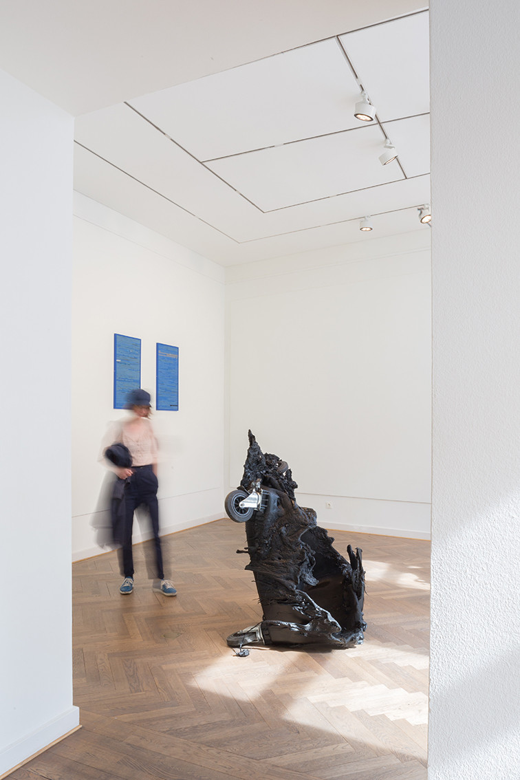 Eine Besucherin läuft um eine verbrannt Mülltonne