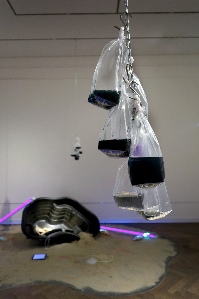 Detailansicht: Von der Decke hängende Ketten mit Beuteln, gefüllt mit Slime