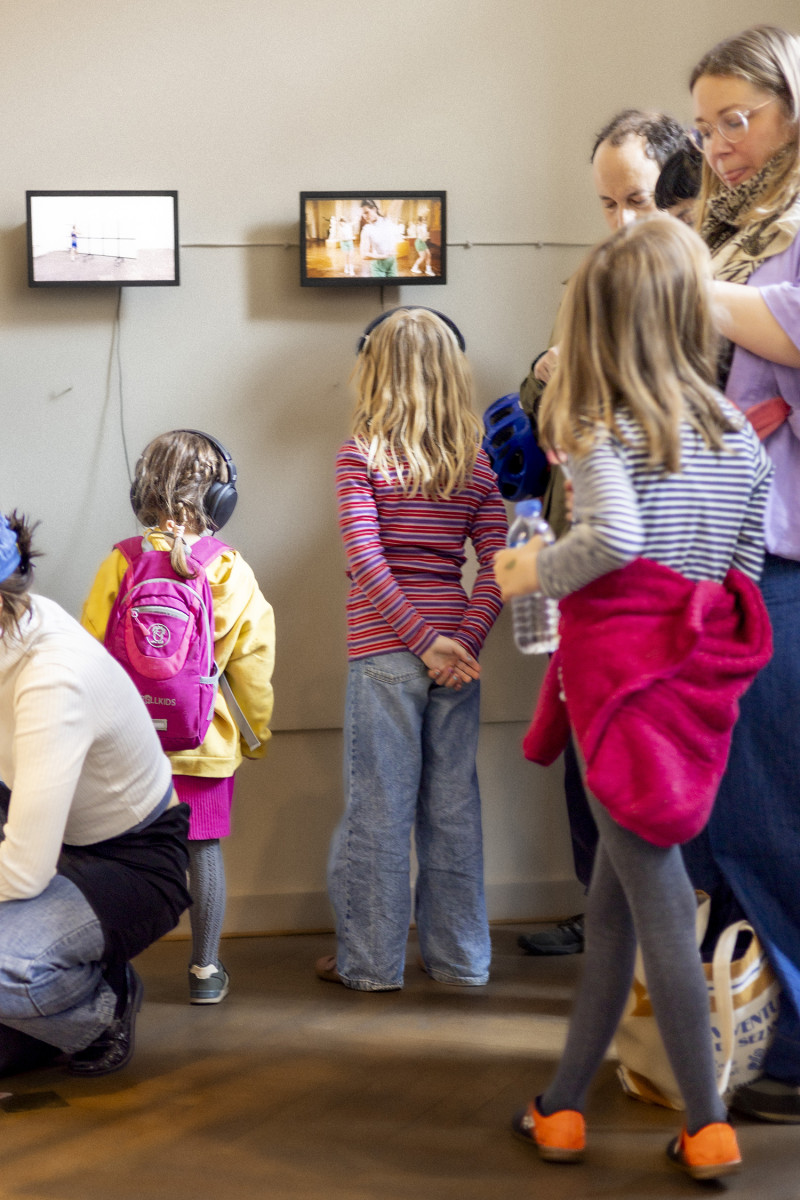 Menschen stehen vor zwei Bildschirmen mit Videos von Performances