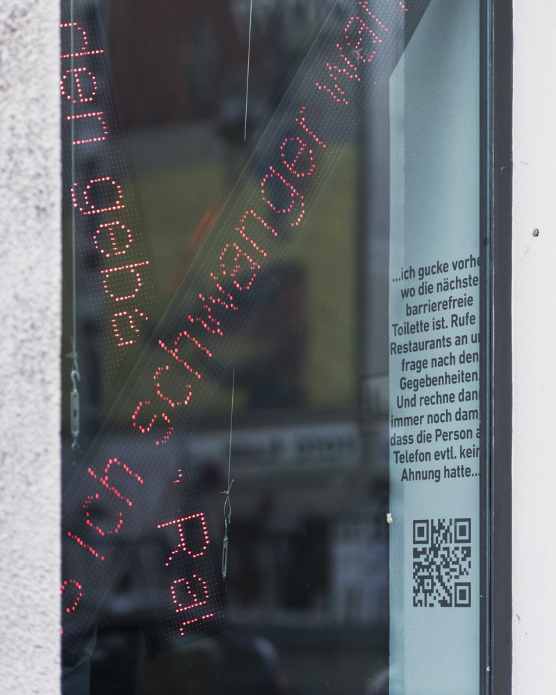 Hinter einer Fesnterscheibe sind Leuchtschriften zu sehen